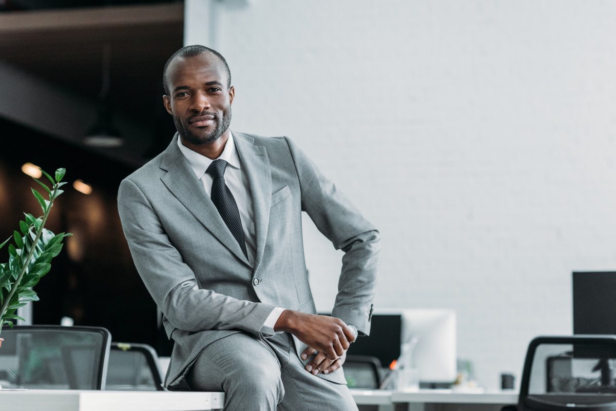 african american businessman sitting on table in office