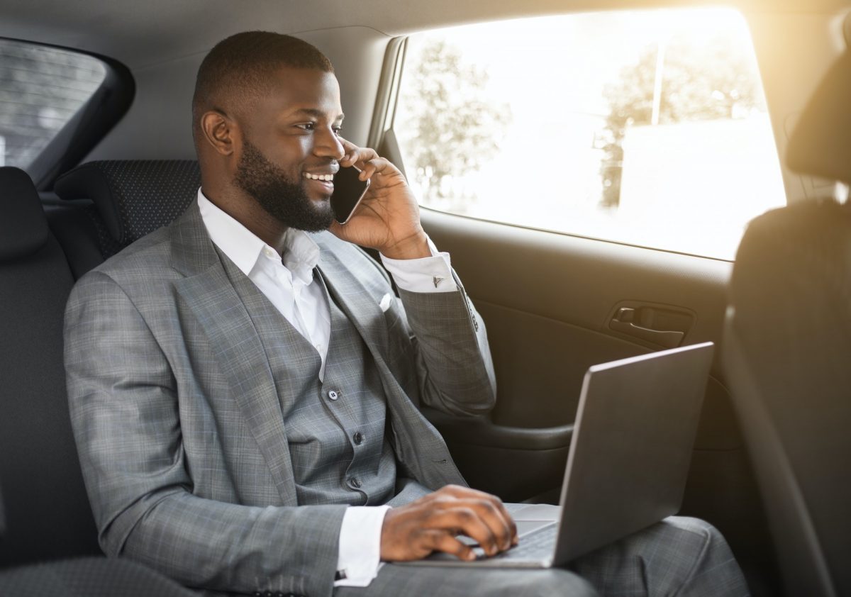 Happy black businessman talking on phone in car